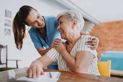 Smiling nurse helping happy senior woman at home visit